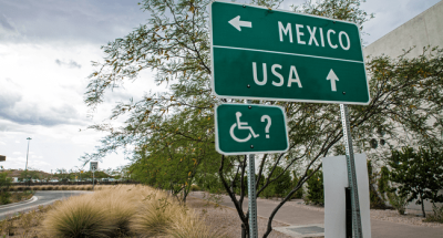A road sign that reads Mexico with an arrow to the left, and USA with an arrow pointing forward.