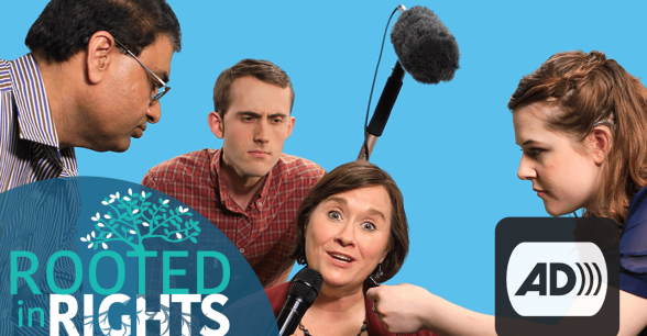 A video production scene featuring four people. One speaking into a microphone. Another fixing the person's hair. A third holding a boom mic and a fourth holding the microphone. The Rooted in Rights logo is in the left corner and the Audio Description symbol is in the right corner.