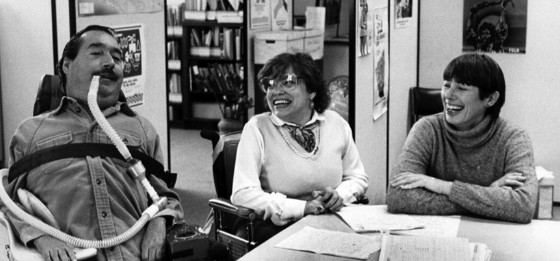 Ed Roberts and Judy Heumann in a black and white photo together, talking and smiling.