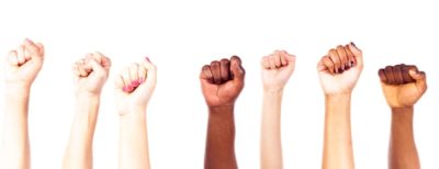 Fists of people of different skin colors raised together in the air.