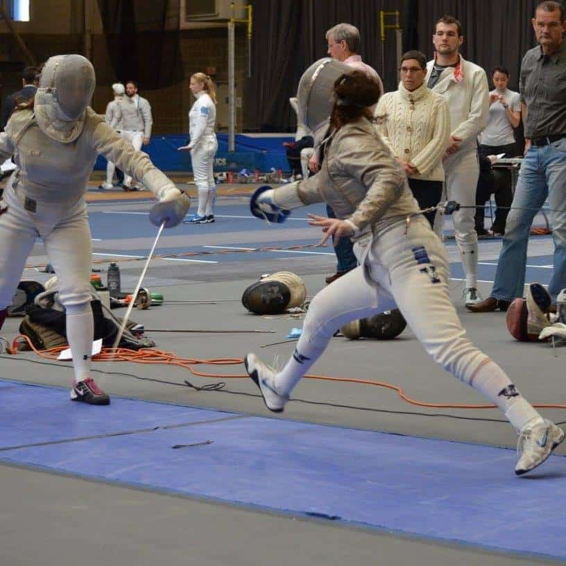 A photo of Lillie Lainoff fencing at the Brandeis Invitational in 2016, where Yale went 5-0 and upset No. 8 St. John's in the process, 18-9. She is mid lunge, both her feet are off the ground. 
