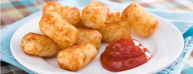 A plate of tater tots with a dollop of ketchup.