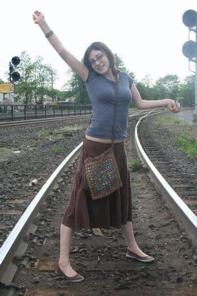 Hannah on a railroad track, her arms up in the air.