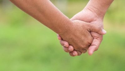 two hands holding together on blurred green background