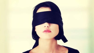 A woman wearing a black fabric blindfold.