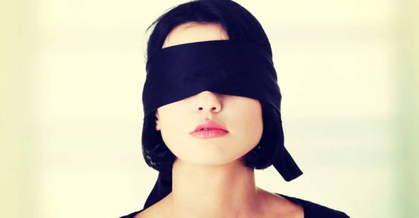A woman wearing a black fabric blindfold.