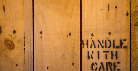 Wooden shipping crate with the words "handle with care" printed on it.