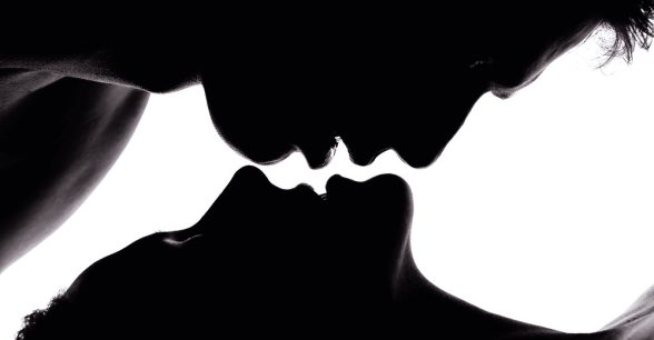 Shadows of two people about to kiss, one hovering over the other's lips.