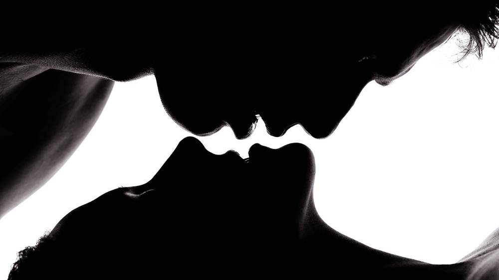Shadows of two people about to kiss, one hovering over the other's lips.