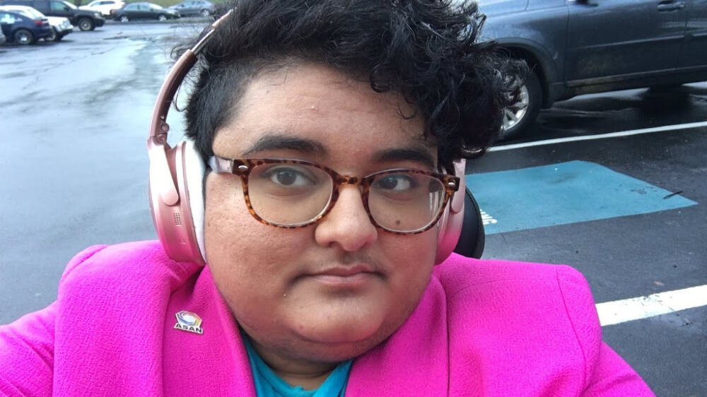 Photo of the author wearing pink headphones and a hot pink jacket.