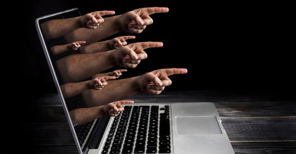 Hands with fingers pointing outward coming out of a laptop screen