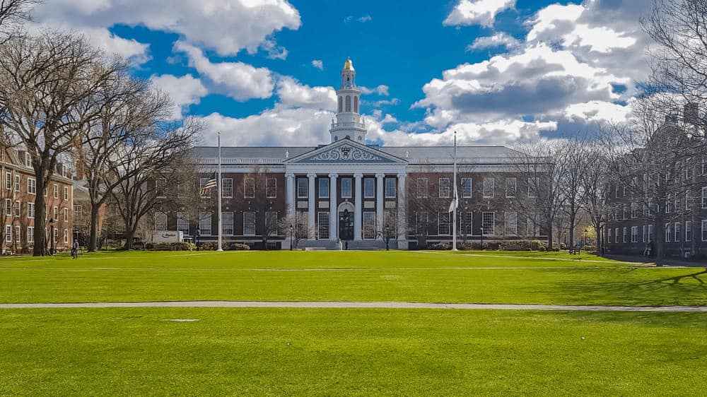 A photo of a building on the Harvard campus, surrounded by a bright blue cloudy sky and bright green grass.