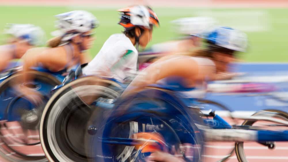 A blurred photo of wheelchair racers in motion.
