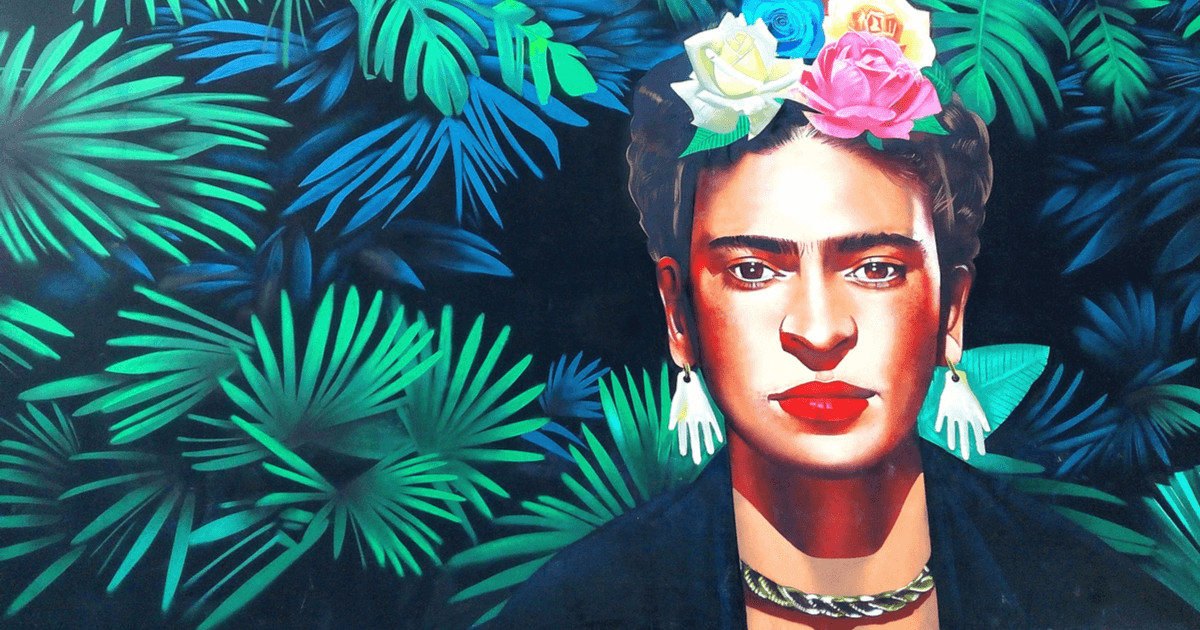 A painting of Frida Kahlo who has multicolored flowers in her hair, bright red lipstick, and earrings shaped like hands. She is against a background of bright green leaves.