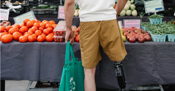 A person with a prosthetic leg shopping at a market
