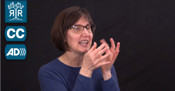 Debra, a white woman with short brown hair and glasses, signs to camera.
