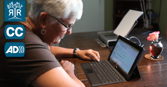 An elder woman is typing on a laptop.