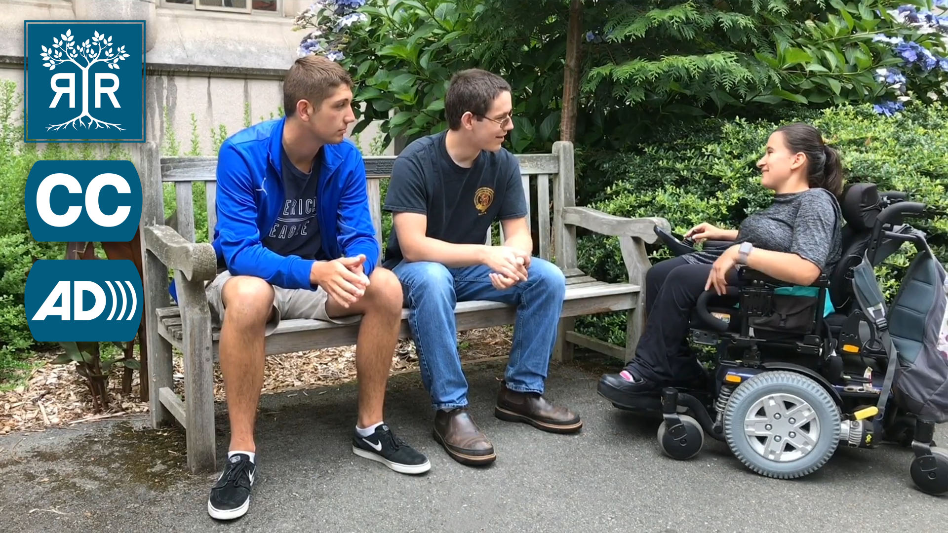 Two students face another who uses a power chair.