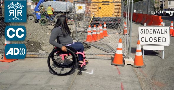 A woman with long black hair pushes her wheelchair towards a sign that says, "Sidewalk Closed", infornt of a construction site.
