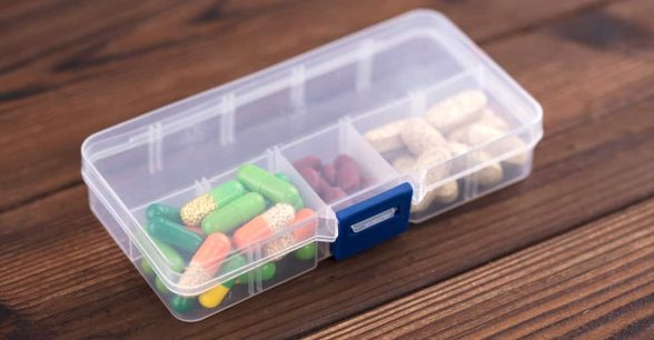 Close up of a clear, plastic pill organizer with pills of various colors inside.