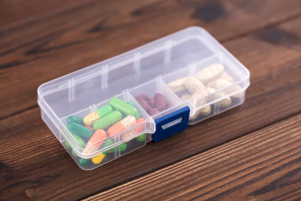 Close up of a clear, plastic pill organizer with pills of various colors inside.